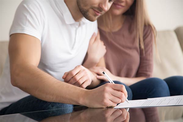 Young man signing document with wife
