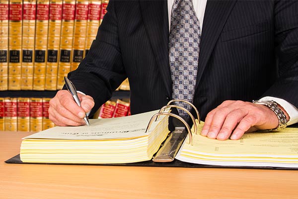 Attorney writing a contract with law books behind him