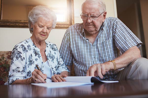 Elderly couple looking over a document. Woman signing.