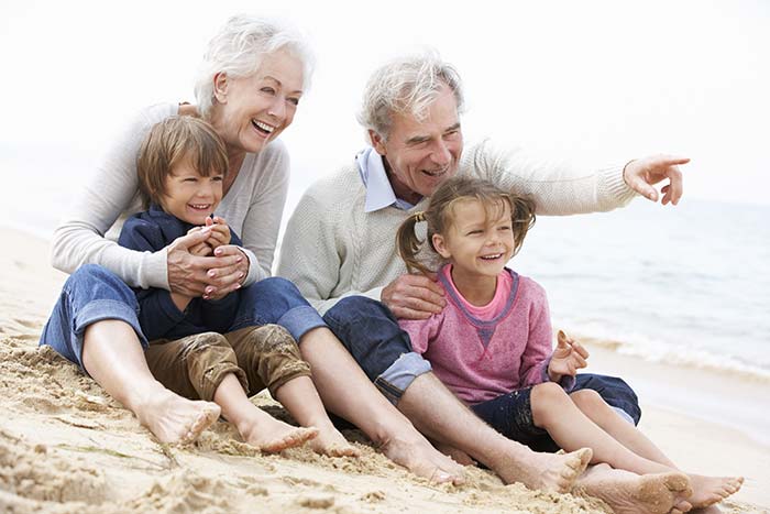 Elderly couple on the beach with 2 grand children